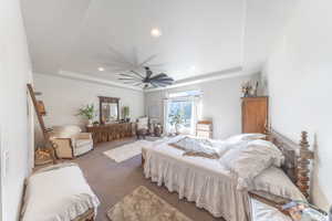 Carpeted bedroom with a raised ceiling, recessed lighting, and a ceiling fan