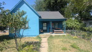 View of front of property with covered porch, a shingled roof, and stucco siding
