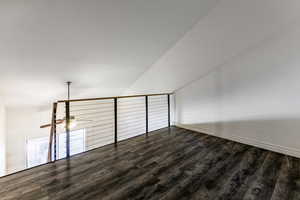 Bonus room with dark wood-style floors and lofted ceiling