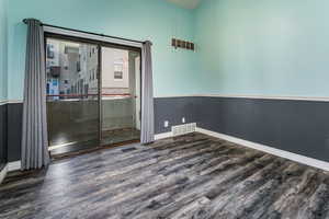 Spare room with dark wood-type flooring and a towering ceiling