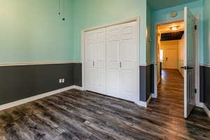 Unfurnished bedroom featuring dark wood-style floors and a closet