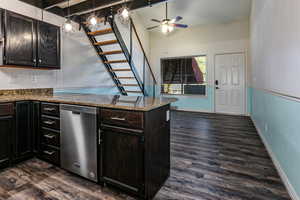 Kitchen featuring beamed ceiling, dark stone counters, stainless steel dishwasher, a peninsula, and dark wood-style floors