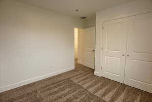 Bedroom #1 with dark colored carpet and a closet