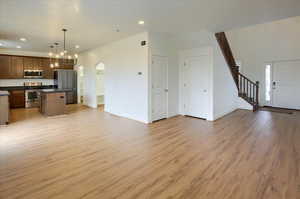 Kitchen with open floor plan, dark countertops, a kitchen island, decorative light fixtures, and appliances with stainless steel finishes