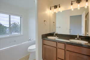 Master bathroom featuring double vanity, a bath, and tile patterned floors