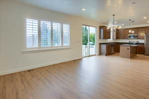 Kitchen with a chandelier, dark countertops, decorative light fixtures, open floor plan, and a kitchen island