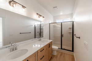Primary Bathroom with light wood finished floors, double vanity, and a stall shower