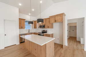 Kitchen with decorative backsplash, light wood finished floors, a center island, appliances with stainless steel finishes, and decorative light fixtures