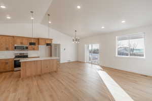 Kitchen featuring decorative backsplash, a center island, appliances with stainless steel finishes, pendant lighting, and light wood finished floors