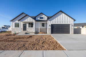 Modern inspired farmhouse featuring board and batten siding, concrete driveway, an attached garage, and a shingled roof