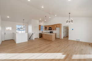 Kitchen with a chandelier, open floor plan, a kitchen island, high vaulted ceiling, and recessed lighting