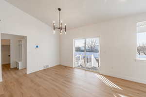Unfurnished dining area featuring plenty of natural light, light wood-type flooring, and a chandelier