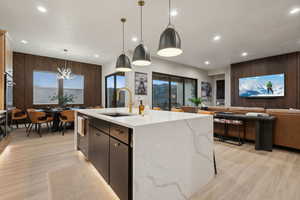 Kitchen featuring decorative light fixtures, wood walls, recessed lighting, open floor plan, and light stone countertops