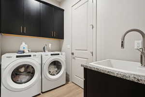 Washroom featuring cabinet space, light wood finished floors, and washer and dryer