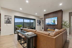 Living area with a glass covered fireplace, light wood finished floors, and recessed lighting