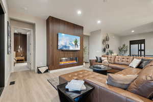 Living room with recessed lighting, a glass covered fireplace, and light wood-style floors