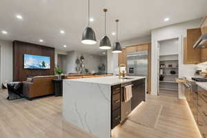 Kitchen with open floor plan, recessed lighting, a kitchen island with sink, hanging light fixtures, and light wood-type flooring