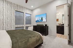 Bedroom with light colored carpet, recessed lighting, ceiling fan, and ensuite bath