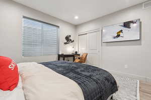 Bedroom with wood finished floors, a closet, and recessed lighting