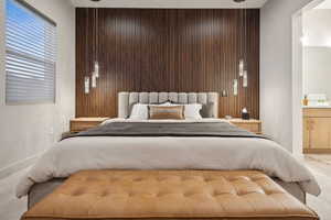 Bedroom with carpet, wooden walls, ensuite bathroom, and an accent wall