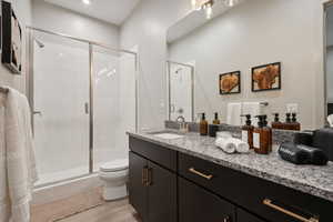 Bathroom with vanity, light wood-style floors, and a shower stall