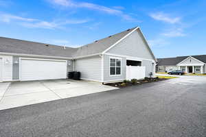 View of side of home with roof with shingles, concrete driveway, and an attached garage