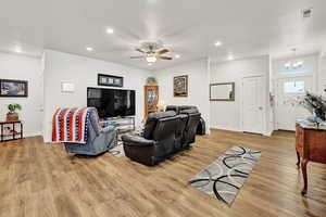 Living room featuring recessed lighting, light wood finished floors, a ceiling fan, and a chandelier