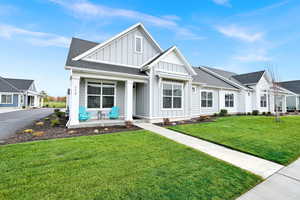View of front of house with board and batten siding, a front yard, a shingled roof, and a porch