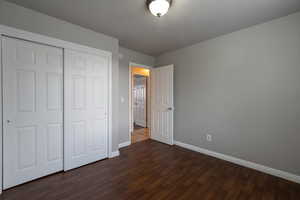 Unfurnished bedroom with a closet and dark wood finished floors
