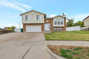 View of front of home featuring concrete driveway, a chimney, brick siding, and a garage