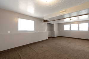 Carpeted spare room featuring a textured ceiling