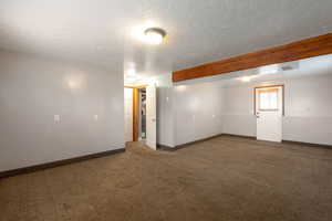 Basement with dark carpet and a textured ceiling