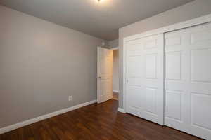 Unfurnished bedroom featuring dark wood finished floors and a closet