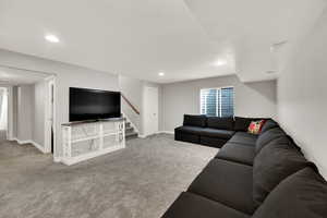 Living area with light carpet, recessed lighting, and stairs