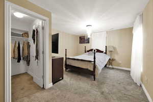 Bedroom featuring light carpet and a walk in closet