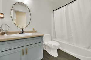 Bathroom with vanity, dark tile patterned flooring, and shower / tub combo
