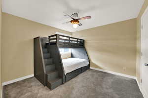 Carpeted bedroom with a ceiling fan and baseboards