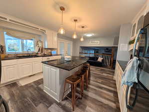 Kitchen featuring tasteful backsplash, white cabinets, a breakfast bar area, and black appliances