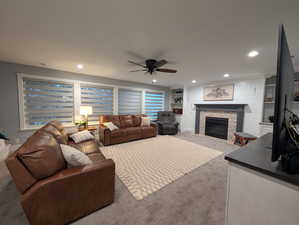 Living room featuring carpet floors, a fireplace, recessed lighting, ceiling fan, and built in shelves
