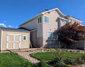 View of home's exterior featuring brick siding, a yard, and a storage shed