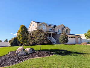 View of front of home featuring a porch, solar panels, brick siding, and stucco siding