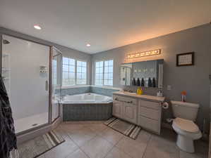 Bathroom featuring a bath, vanity, a stall shower, light tile patterned floors, and recessed lighting