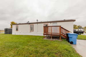 Back of property with a lawn, a deck, and an outdoor structure