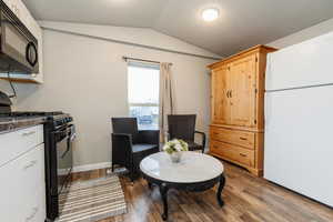 Living area featuring a textured ceiling, vaulted ceiling, and dark wood-style floors