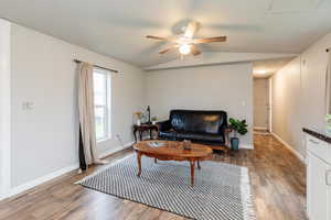 Living area with light wood-style floors, lofted ceiling, and ceiling fan
