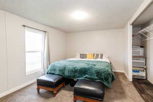 Carpeted bedroom with a textured ceiling and baseboards
