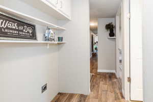 Washroom featuring light wood-style flooring, a textured ceiling, and electric dryer hookup
