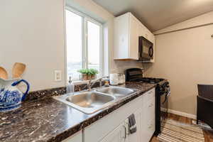 Kitchen featuring black appliances, dark countertops, white cabinetry, dark wood finished floors, and a textured ceiling