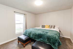 Bedroom featuring a textured ceiling, carpet floors, and a decorative wall