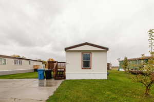 Back of house featuring a lawn and a wooden deck
